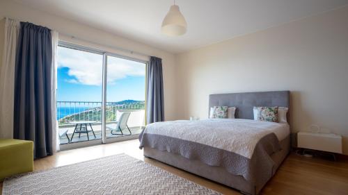 Un dormitorio con una cama y una ventana grande. en Estrela do Mar - by LovelyStay - Lovely, Sun Filled Villa, en Calheta