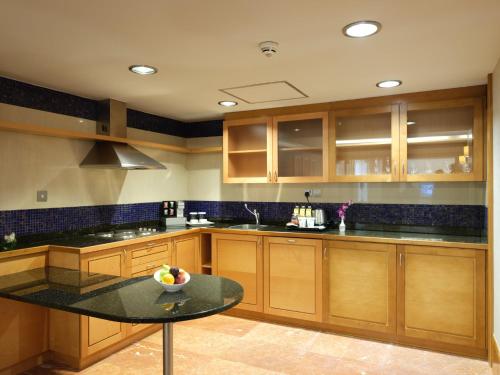 a kitchen with wooden cabinets and a black counter top at Holiday Inn Kuwait Al Thuraya City by IHG in Kuwait