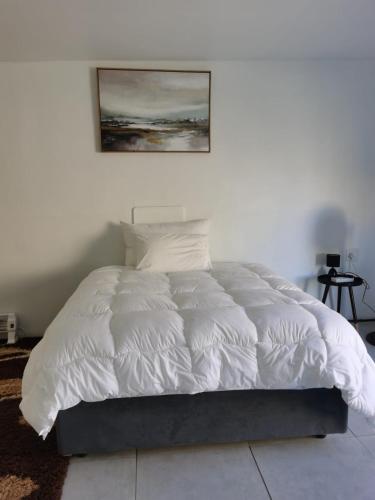 a bedroom with a white bed with a picture on the wall at Mamo in Maseru