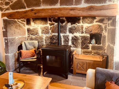 - une cheminée en pierre dans le salon avec une cuisinière dans l'établissement Maison authentique au cœur des montagnes, 8pers, à Thiézac