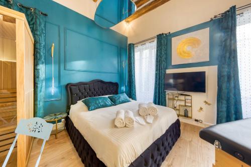 - une chambre bleue avec un lit et des serviettes dans l'établissement Suite bien être - jacuzzi et sauna / love room, à Arpajon
