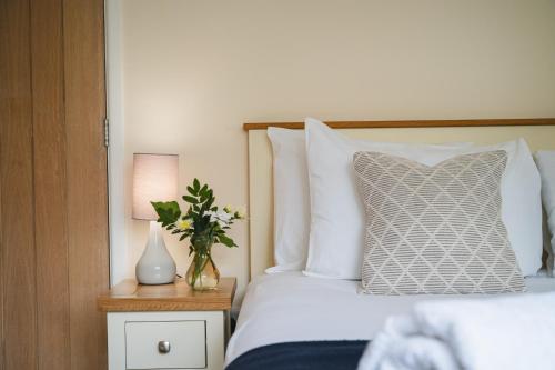 a bedroom with a bed with a pillow and a vase of flowers at Little Hill Farm Villa in Ringwood