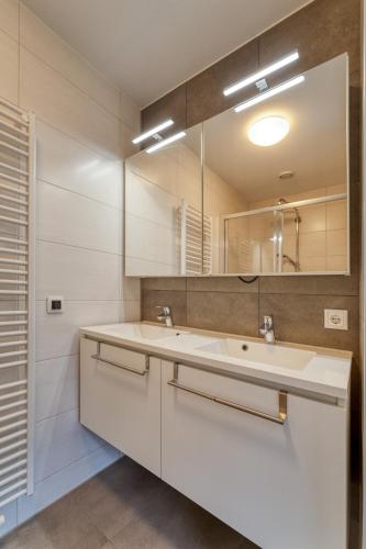 a bathroom with a white sink and a mirror at Zwanebloem 2 in Cadzand