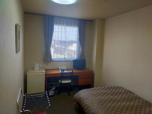 a bedroom with a desk and a bed and a window at Hotel Kurashiki Mizushima Hills in Chidorichō