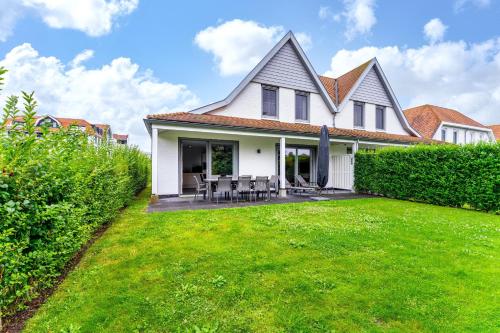 a white house with a grass yard at Zwanebloem 2 in Cadzand