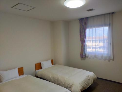 a room with two beds and a window at Hotel Kurashiki Mizushima Hills in Chidorichō