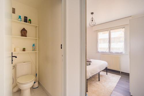 - une salle de bains avec toilettes et un lit dans une chambre dans l'établissement Escapade Confort au Cœur de la Ville Cosy&Moderne, à Saint-Julien-en-Genevois