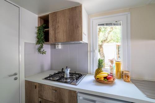a kitchen with a stove and a bowl of fruit on the counter at Club del Sole Adriatico Cervia Easy Camping Village in Cervia
