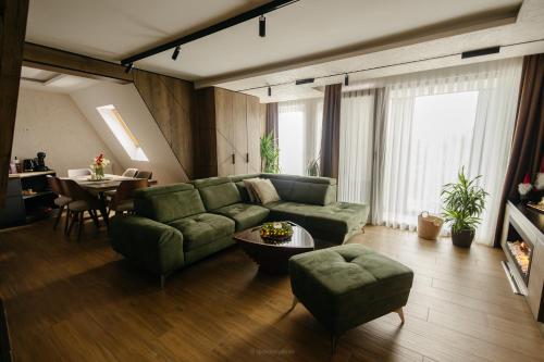 a living room with a green couch and a table at BOROVI PRESIDENT SPA Apartment in Divčibare
