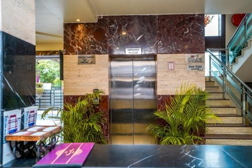 a lobby with a elevator and stairs with plants at The Golden Apple in Lucknow