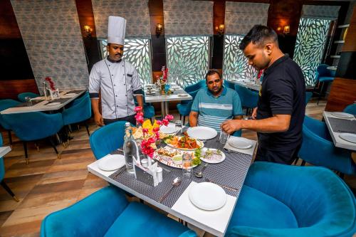 three men standing around a table in a restaurant at The Golden Apple in Lucknow