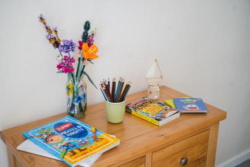 a wooden table with books and a vase of flowers at Little Hill Farm Villa in Ringwood