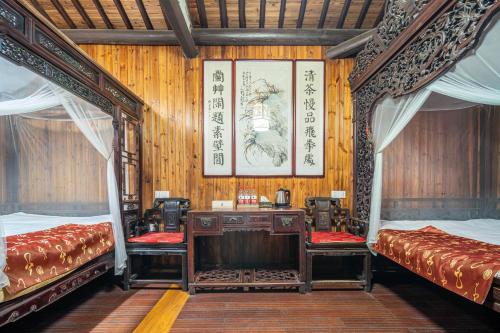 a room with two beds and a desk in it at Nanxun Luohua Old House Inn in Huzhou