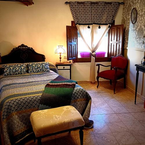 a bedroom with a bed and a chair and a window at Casa rural en Buendía -la Galera con 4 dormitorios in Buendía