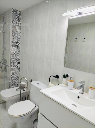 a bathroom with a sink and a toilet and a mirror at El rincón Del Prado apartamento con 4 AC in Gandía