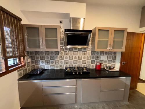 a kitchen with a stove and a microwave at Arcade Serenity Suites in Chikmagalūr
