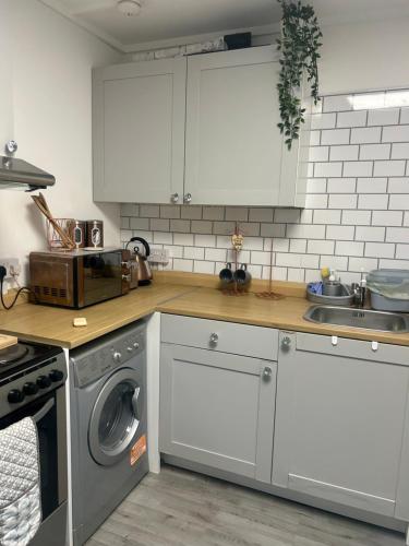カーディフにあるQuaint Space, 10 minutes walk from Cardiff Centralのキッチン(白いキャビネット、洗濯機付)
