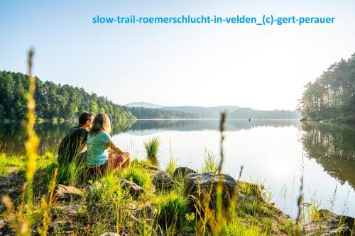 a couple sitting on the shore of a lake at Hotel Gabriel in Keutschach am See