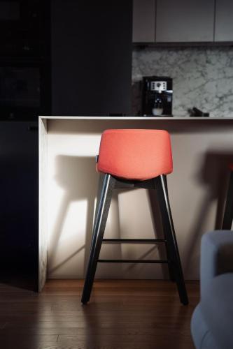 a red stool sitting in front of a kitchen counter at Luxury Sunny Home - Free Garage, Metro, Balcony, PS5, 2nd parking on request in Prague
