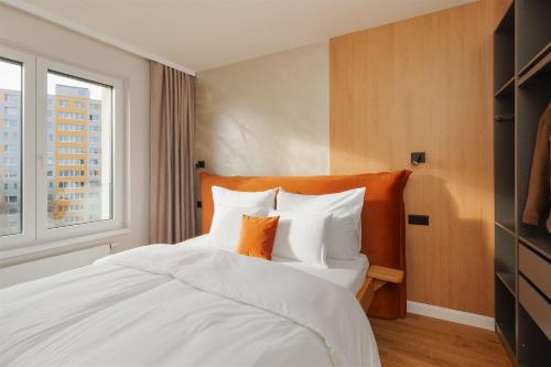 a bedroom with a bed with white pillows and a window at Luxury Sunny Home - Free Garage, Metro, Balcony, PS5, 2nd parking on request in Prague