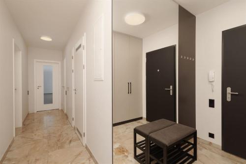 a hallway with black doors and a stool at Luxury Sunny Home - Free Garage, Metro, Balcony, PS5, 2nd parking on request in Prague