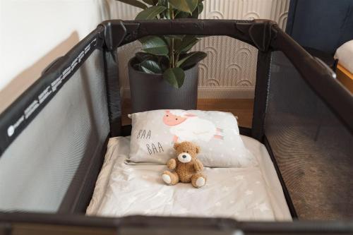 a teddy bear sitting in a crib with two pillows at Luxury Sunny Home - Free Garage, Metro, Balcony, PS5, 2nd parking on request in Prague