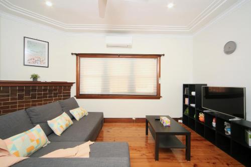 a living room with a couch and a television at Sydney, Bexley North holiday home 3bedrooms, free parking, close to Train station and CBD in Sydney