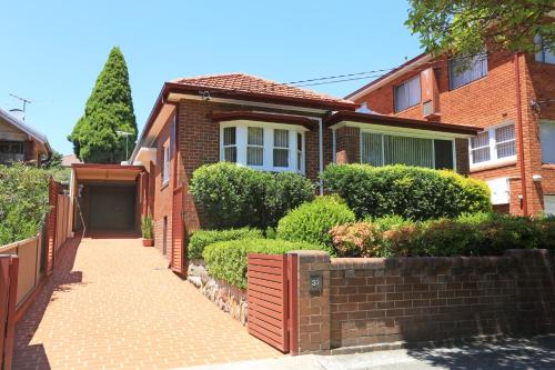 a brick house with a fence and a sidewalk at Sydney, Bexley North holiday home 3bedrooms, free parking, close to Train station and CBD in Sydney