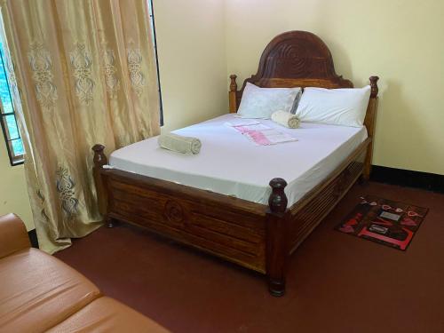 a bed with a wooden headboard in a room at Ushongo Econostay in Wanga