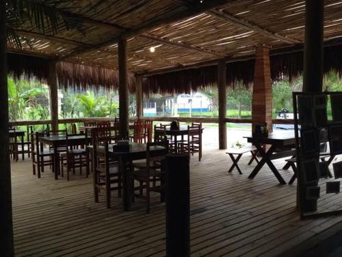 a restaurant with wooden tables and chairs and a deck at Pousada Toka do Lula - Oficial in Peruíbe