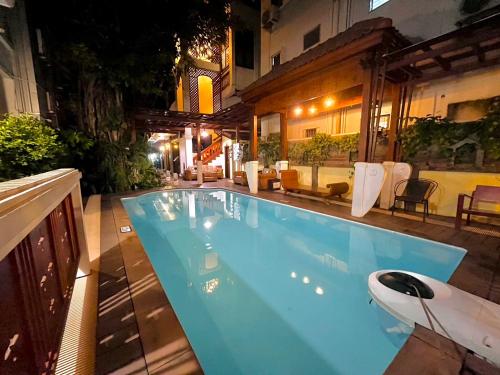 a large blue swimming pool in a backyard at night at Sripat Guesthouse SHA Extra Plus in Chiang Mai