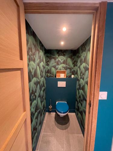 La salle de bains est pourvue de toilettes bleues et de plantes vertes. dans l'établissement La Casa di Nona, à Honfleur