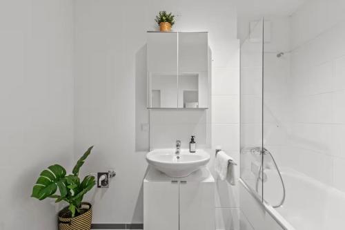 a white bathroom with a sink and a shower at Fast Wifi - 3 min walk to metro - On-Site Parking for 19,90 Eur in Vienna