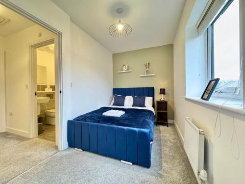 a bedroom with a blue bed and a bathroom at Stylish 2 Bedroom Home Near Lake with Free Parking & Garden in Doncaster