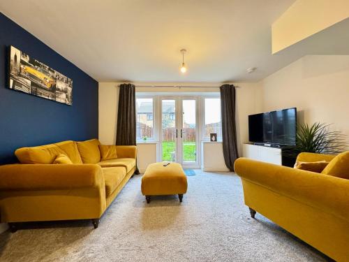a living room with two yellow couches and a tv at Stylish 2 Bedroom Home Near Lake with Free Parking & Garden in Doncaster