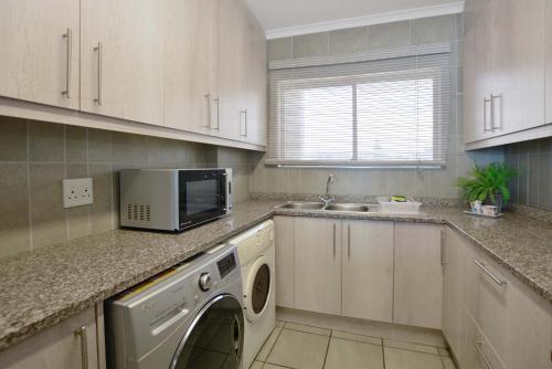 a kitchen with a washer and dryer on the counter at Beach Daze in Bloubergstrand