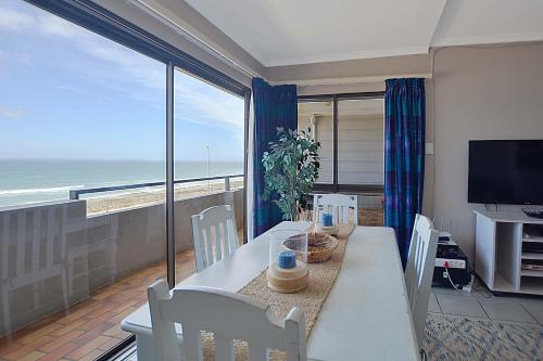 a dining room with a table and a view of the ocean at Beach Daze in Bloubergstrand