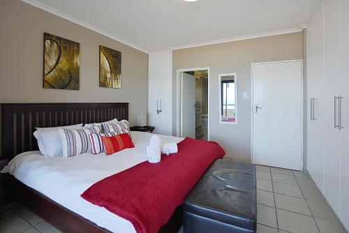 a bedroom with a large bed with a red blanket at Beach Daze in Bloubergstrand