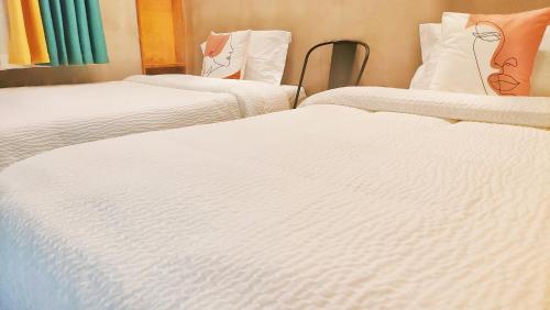 three beds in a room with white sheets at A&G Apartment in Zhangjiajie