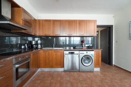 a kitchen with wooden cabinets and a washing machine at Seafront Protaras Apartments in Protaras