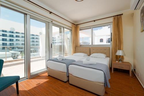 two beds in a room with large windows at Seafront Protaras Apartments in Protaras