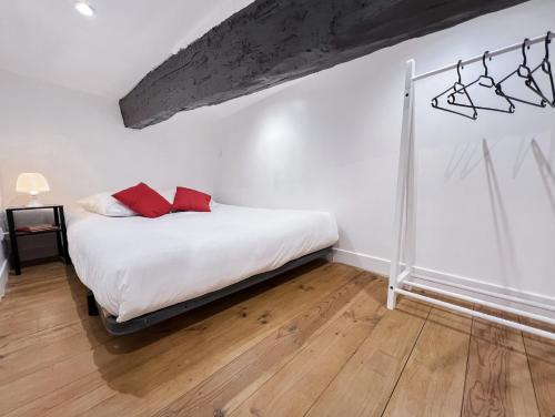 - une chambre avec un lit doté d'oreillers rouges dans l'établissement L'Escapade - Charmant studio au cœur du village, à Saint-Maximin-la-Sainte-Baume
