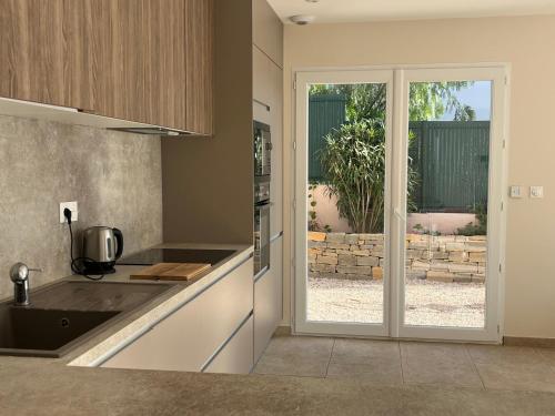 une cuisine avec une porte menant à une terrasse dans l'établissement Villa Ischia Vue Mer, à Bandol