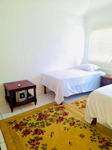 a bedroom with a bed and a table and a rug at Country Club House Retreat - 2 bedroom House with Pool near Montego Bay Airport and Beach Strip in Montego Bay