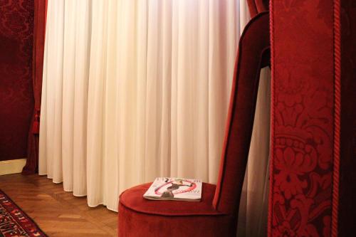 a book sitting on a red chair in front of a curtain at Hotel Ai Cavalieri di Venezia in Venice