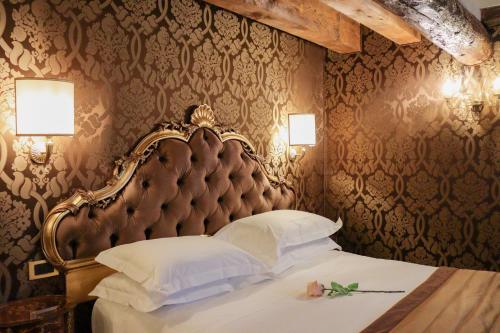 a bedroom with a large bed with a large headboard at Hotel Ai Cavalieri di Venezia in Venice