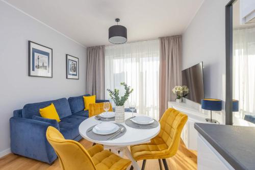 a living room with a blue couch and a table and chairs at Elegant Apartment in Warsaw with Parking and Desk for Remote Work by Noclegi Renters in Warsaw