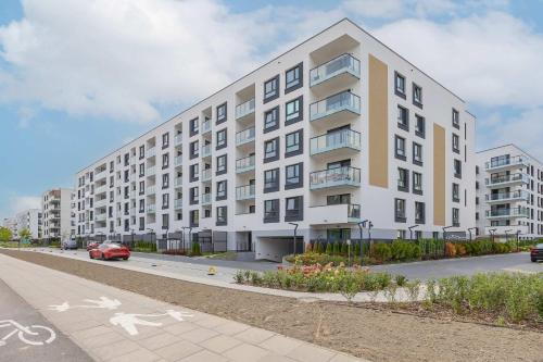 a large white apartment building on a street at Elegant Apartment in Warsaw with Parking and Desk for Remote Work by Noclegi Renters in Warsaw
