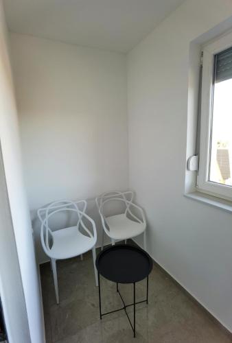 two white chairs and a table in a room at Vila Nika in Banja Luka