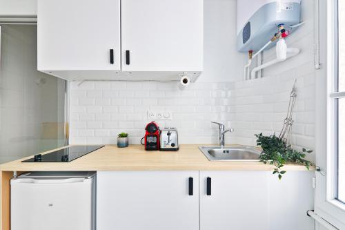 une cuisine avec des armoires blanches et un évier dans l'établissement Studio Quartier Tour Eiffel 9 Free Netflix, à Paris